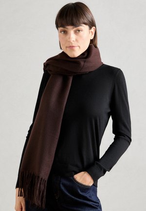 Brown scarf made from a soft material, draped loosely around the neck. Features fringe detailing at the ends. Worn over a black top.
