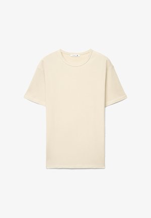 T-shirt a maniche corte color crema con tessuto strutturato, scollo tondo e vestibilità rilassata, con etichetta all'interno del colletto.