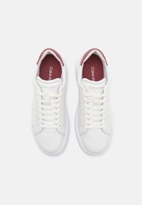 Sneaker bianche in pelle con finitura liscia, caratterizzate da dettagli bordeaux sul collo e soletta imbottita, con lacci bianchi.