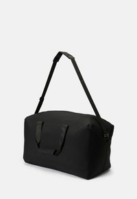 Black duffel bag made of durable fabric, featuring two top handles and an adjustable shoulder strap for versatile carrying options.