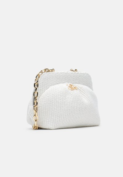 Sac à main en tissu blanc texturé avec une bandoulière en chaîne dorée et un petit emblème papillon doré sur le devant, présenté sur un fond clair uni.