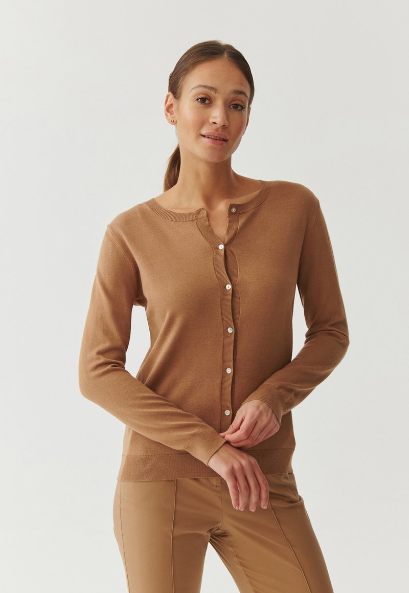 Bruine, lange mouwen cardigan met een ronde halslijn, subtiele geribbelde zoom en een knoopsluiting met lichtgekleurde knopen. Zachte textuur.