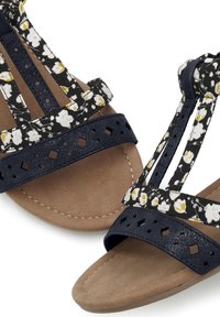 Stoffen sandalen met florale banden in marineblauw en wit, een effen marineblauwe band, geperforeerde textuur en een tan, gladde voetbed.