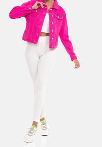 Fuchsia denimjakke med frontlommer og sølvfarvet hardware, kombineret med hvide ribstrikkede leggings og hvide sneakers med neongrønne detaljer.