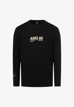 Schwarzes langärmliges T-Shirt aus Baumwolle mit weißem Text "AMS 89" und Markenlogo. Enthält ein kleines Etikett-Detail am linken Ärmel.