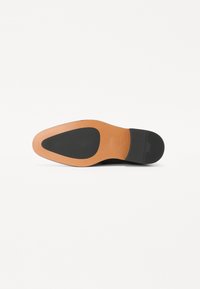 Suola di scarpa in pelle nera con design a punta. Presenta una parte in gomma nera liscia e un bordo in pelle marrone chiaro.