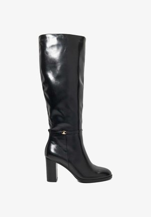 Zwarte leren kniehooglaars met blokhak en dunne enkelband met een kleine gouden gesp, schuin naar links op een witte achtergrond.