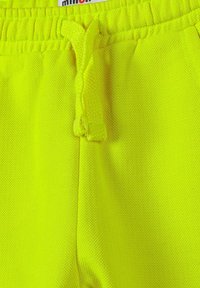 Shorts de sport jaune vif en tissu texturé, dotés d'une taille élastique avec cordon de serrage et d'un intérieur lisse.