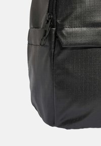 Černý batoh s texturovaným povrchem, elegantním designem, zipovým uzávěrem a boční kapsou, vyrobený z odolného, voděodolného materiálu.