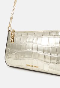 Metallic gold handbag with a crocodile pattern, features a black trim, gold chain strap, and a zipper closure. Textured and sleek design.