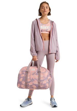 Duffle bag with a pink leaf pattern, grey accents, zip closure, and dual handles. Styled with a matching athletic outfit in light purple.