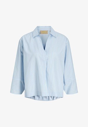 Gaiši zila blūze ar plānām vertikālām sarkanām svītrām, V formas kaklu un trīs ceturtdaļu garuma piedurknēm ar platām aprocēm.