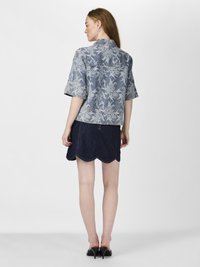 Kortärmad denimjacka i ljusblått med blommönster. Kombineras med en mörk denimkjol med scalloped kant och svarta klackmules.