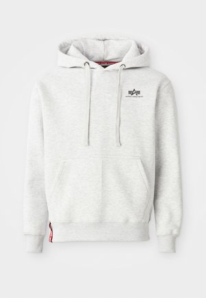 Helle graue Kapuzenjacke aus weichem Stoff. Verfügt über eine Kängurutasche, Kordeln und ein kleines schwarzes Logo auf der Brust. Gerippte Bündchen.