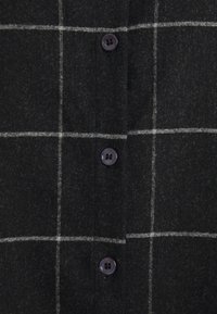 Schwarz kariertes Hemd mit weißen Linien, ausgestattet mit lila Knöpfen. Das Material hat eine weiche, strukturierte Oberfläche und ein klassisches Kragen-Design.