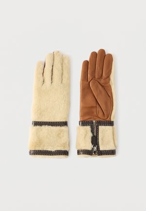 Pair of gloves featuring a soft beige shearling exterior and a brown leather palm, with black accents and a zipper detail at the wrist.