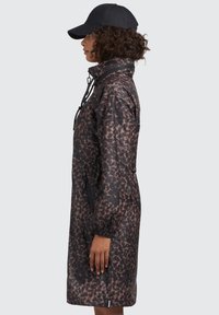 Impermeabile con stampa leopardata in tonalità di marrone e nero. Presenta un cappuccio, un collo con cordino, polsini elasticizzati e una tasca con zip.