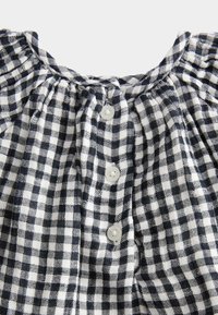 Bawełniana tkanina w kratkę w kolorze granatowym i białym, z marszczonym dekoltem i czterema białymi guzikami z przodu.