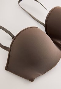 Sutien maro căptușit cu cupe modelate și bretele reglabile pe un fundal deschis, afișat aplatizat pentru vizibilitatea detaliilor.