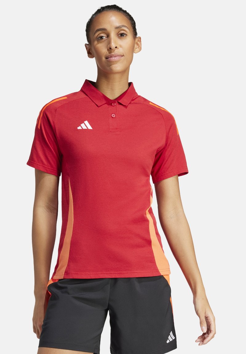 Rotes Polohemd mit orangefarbenen seitlichen Streifen, aus strukturiertem Stoff. Verfügt über einen Kragen und eine Knopfleiste mit drei Knöpfen. Adidas-Logo auf der Brust.