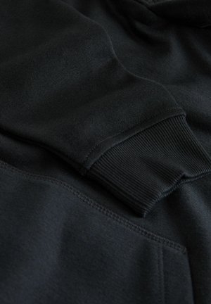 Sort hættetrøje med ribbede manchetter, blød tekstur og en kængurulomme. Sømmen er pæne, og stoffet ser tykt og varmt ud.