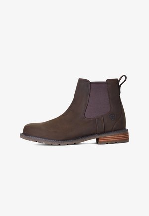Bottines Chelsea en cuir marron avec des panneaux latéraux élastiques et une languette. Présentent une finition texturée et un talon en bois empilé.