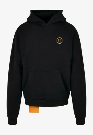 Čierna kapucňová mikina vyrobená z bavlny, s prednou vreckom a rebrovanými manžetami. Malá zlatá emblema na hrudi; viditeľná oranžová visačka na leme.