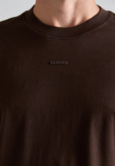 Mørkebrun bomulls T-skjorte med rund hals og en subtil "SANDRO" logo i svart på forsiden, med en jevn, myk tekstur.