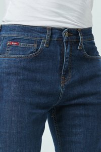 Jean en denim bleu foncé au design ajusté, avec des coutures contrastantes, une fermeture à bouton à l'avant et un petit logo rouge sur la poche.