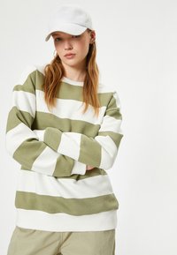Olive zielony sweter w biało-zielone paski, z długimi rękawami, okrągłym dekoltem, ściągaczami przy rękawach i u dołu, wykonany z miękkiego materiału.