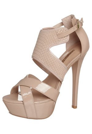 Beige højhælede sandaler med en blank lakfinish og reptilmønstrede detaljer. Har krydsede stropper og en platformsål.