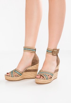 Klínové sandály z hnědé semiše a tkaného juty. Mají vícebarevné tkané pásky a přezku u kotníku, otevřenou špičku.