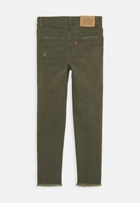 Jeans ajustados color verde olivo con dobladillo desflecado, que cuentan con cinco bolsillos, una etiqueta de cuero y detalles de costura visibles en la parte posterior.