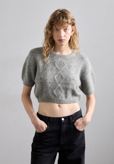 Light gray, cropped knit sweater with a textured pattern, short puffed sleeves, and a ribbed hem, worn with high-waisted black jeans.