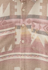 Camicia con bottoni caratterizzata da un motivo geometrico in toni di rosa tenue, beige e marrone; presenta due tasche frontali e una texture di tessuto leggero.