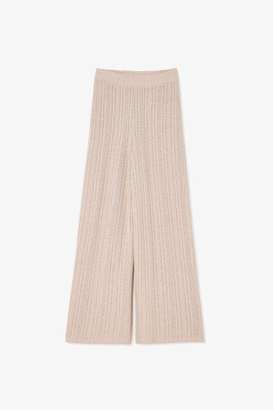 Pantalones de punto de pierna ancha en color beige, con una textura acanalada y rayas verticales, y pequeños cortes en toda la prenda para mayor transpirabilidad. Cintura elástica.