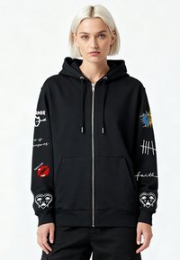 Čierna mikina na zips s grafickými motívmi na rukávoch, vrátane slnka, rúžu na pery a srdcových vzorov, vyrobená z mäkkej, textúrovanej látky.