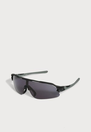 Gafas de sol deportivas envolventes negras y grises con lentes tintadas oscuras y varillas delgadas sobre un fondo claro.