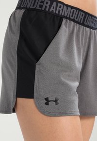 Grå och svarta sportshorts med strukturerad yta, utrustade med ett svart elastiskt midjeband och en liten logotyp på fållen.