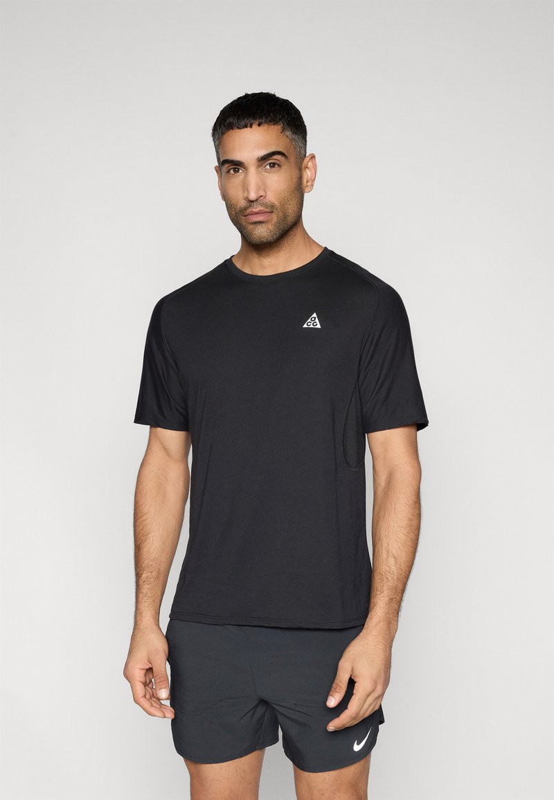 Μαύρο αθλητικό μπλουζάκι με κοντά μανίκια, στρογγυλή λαιμόκοψη και μικρό τριγωνικό λογότυπο στην αριστερή πλευρά. Λείο ύφασμα και εφαρμοστό σχέδιο.