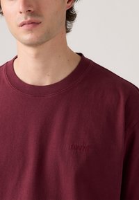Bordeauxfarbene Baumwoll-Pullover mit Rundhalsausschnitt, mit strukturiertem Finish und gesticktem Levi's-Logo auf der Brust. Normale Passform mit geripptem Kragen.