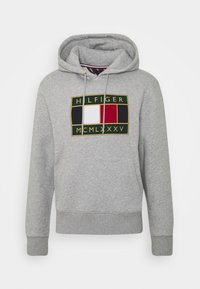 Světle šedá mikina s kapucí, přední klokaní kapsou, šňůrkami na stažení a barevným vyšívaným logem s textem "Hilfiger MCMLXXXV."