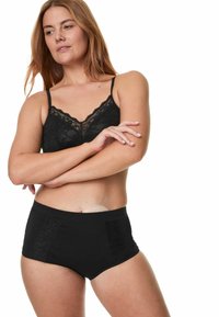 Svart bralette med spetsdetaljer och tunna band, kombinerad med höga svarta trosor som har en strukturerad spetspanel på sidorna.