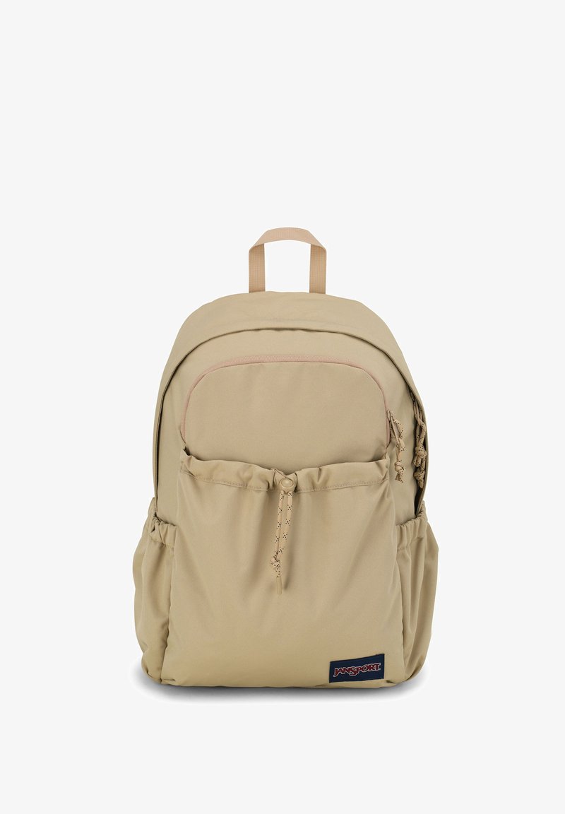 Sac à dos beige avec un tissu texturé, comportant une poche avant, des poches en mesh sur les côtés et une poignée en haut. Comprend des bretelles ajustables.