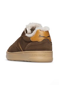 Sneaker alta in suede marrone con una morbida fodera bianca, accento in pelle beige sul tallone e suola in gomma beige. Presenta un marchio discreto sul lato.