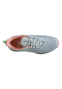 Light gray athletic shoe with textured upper, pink accents, and green heel tab. Features a lace-up design and flexible sole.