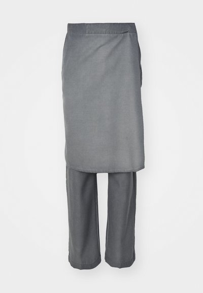 Hall sügav hall kahene komplekt, mis sisaldab pikka otsekutsega toppi ja lahtisi pükse, mõlemad on valmistatud pehmest kangast, millel on minimaalne tekstuur.