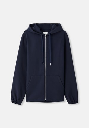 Felpa con zip di colore navy realizzata in tessuto morbido, dotata di cappuccio con coulisse, tasche frontali e polsini elasticizzati. Design semplice e funzionale.