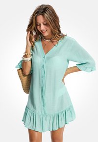 Lichtgewicht, mintgroene overhemdjurk met V-hals, knoopsluiting en gerimpelde zoom. Voorzien van korte mouwen met ruchesdetail.