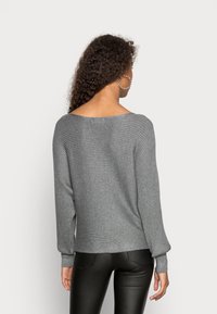 Sweater en maille ribbed gris avec un col large et des manches longues. Le tissu a une texture douce et il présente une coupe décontractée.